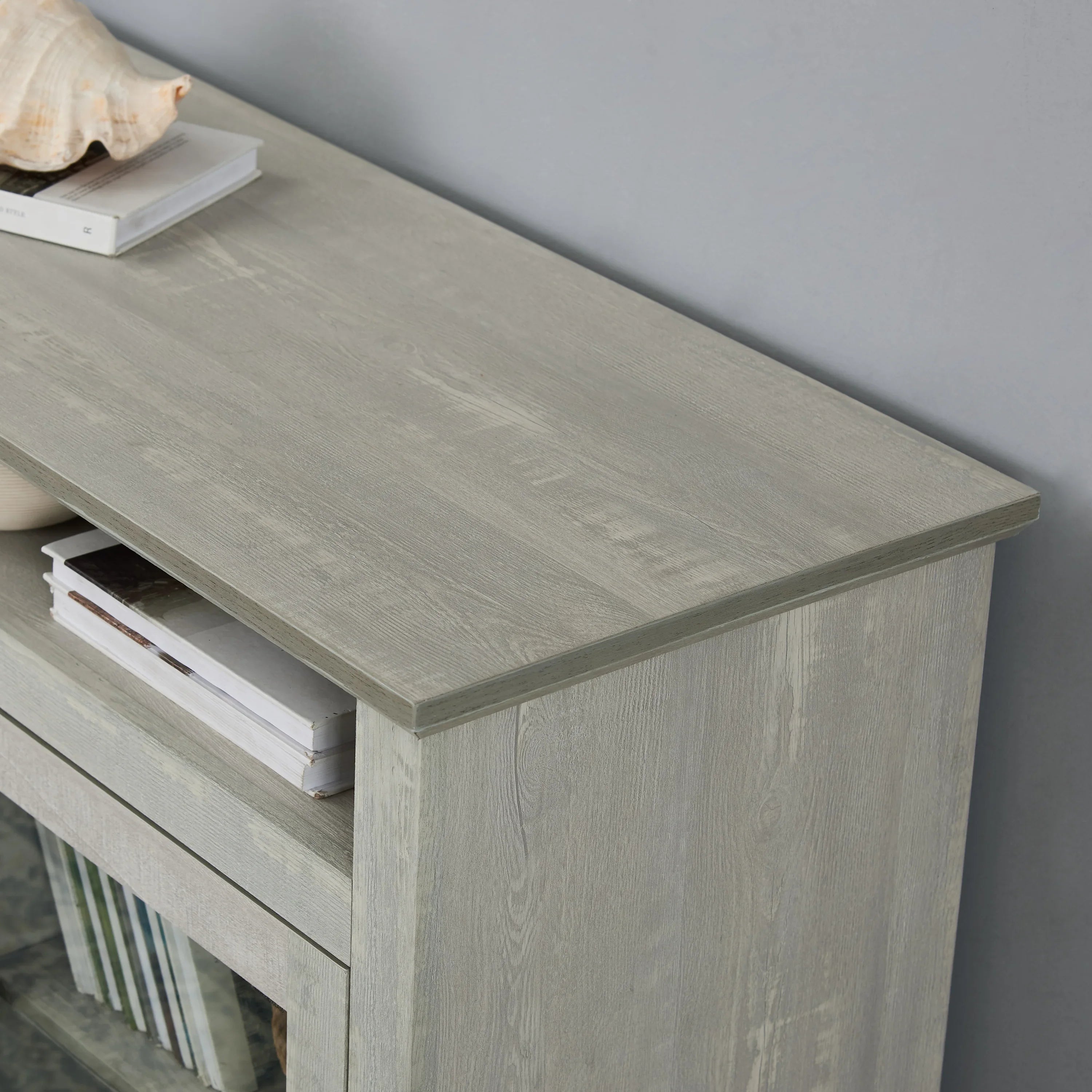 Light gray wood sideboard with books and decor against a modern living room wall
