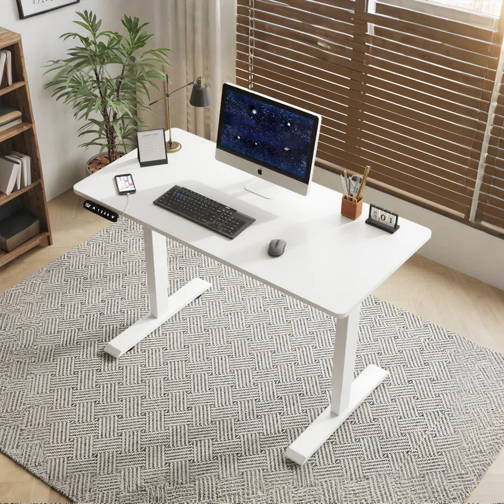 Modern home office with white standing desk, desktop computer, and contemporary decor